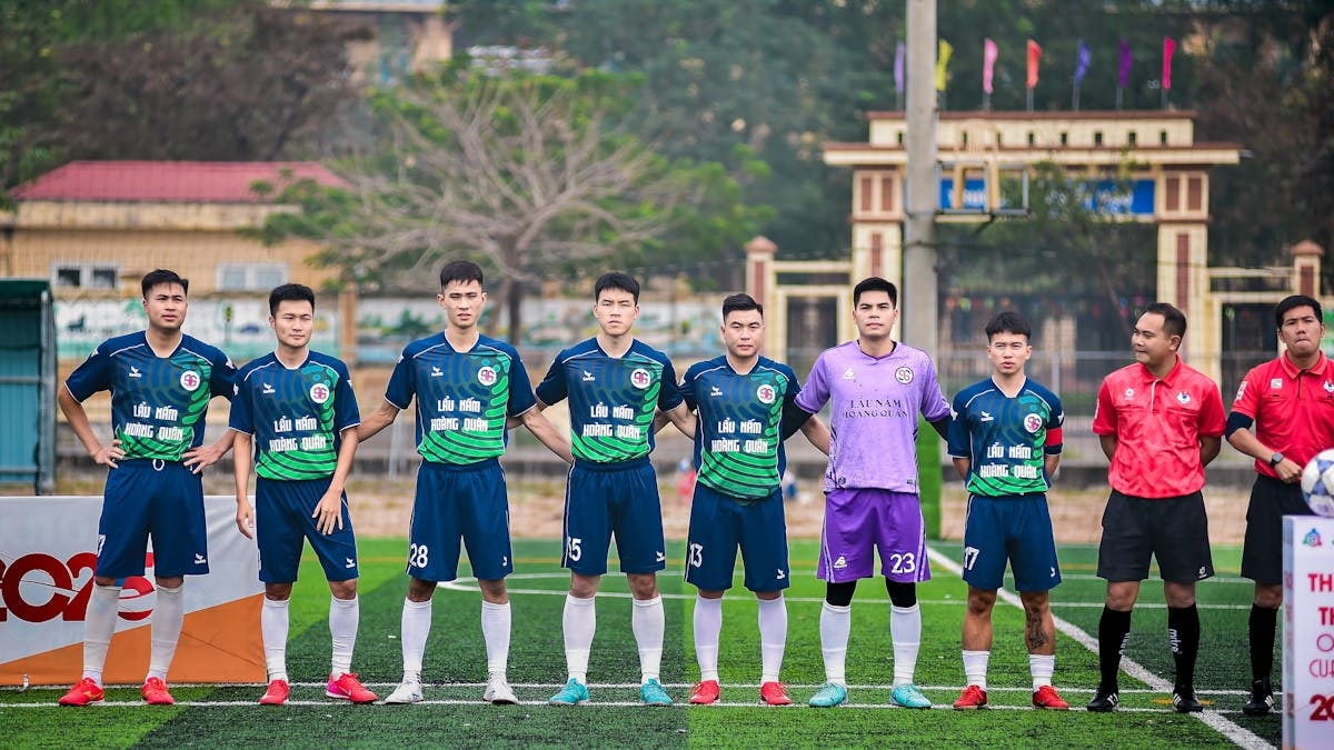 Soccer players and referees standing together on a field in Hà Nội, Vietnam.